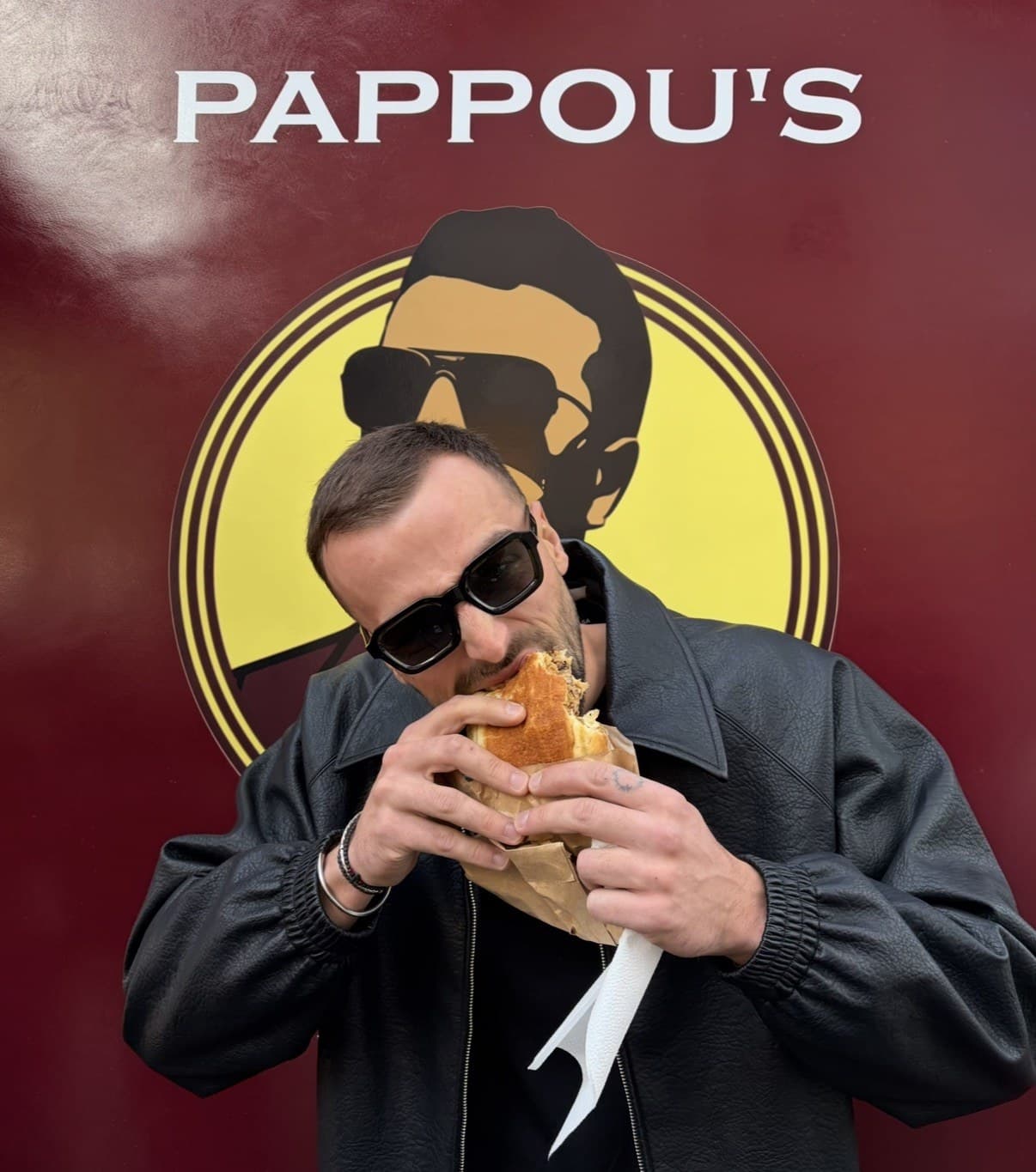 Gast beißt herzhaft in ein Sandwich vor dem Pappou’s Truck